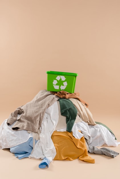 Caixa com símbolo da reciclagem sobre pilha de roupas