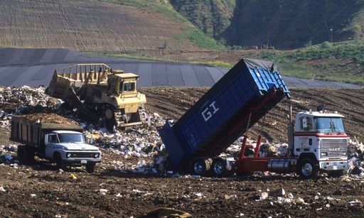 Caminhão com container descartando lixo no solo