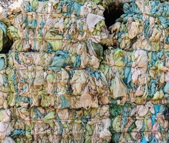Fardos de resíduos têxteis compactados em processo de descarte ou reciclagem, representando a gestão de resíduos na indústria da moda e têxtil.