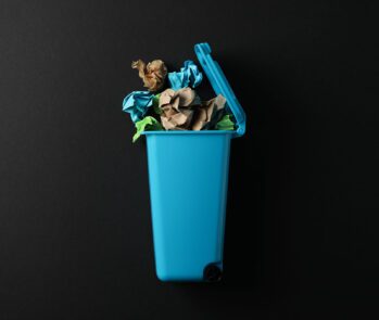 Imagem de uma lixeira azul com papéis coloridos amassados, representando o descarte seletivo de resíduos recicláveis. Ideal para ilustrar conteúdos sobre a ABNT NBR 17100, que estabelece diretrizes e requisitos para a gestão de resíduos sólidos no Brasil. A foto reforça a importância da coleta seletiva, da responsabilidade ambiental e do correto gerenciamento de resíduos nas empresas e na sociedade.