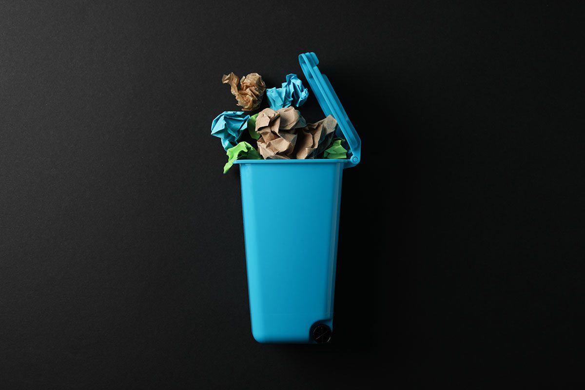 Imagem de uma lixeira azul com papéis coloridos amassados, representando o descarte seletivo de resíduos recicláveis. Ideal para ilustrar conteúdos sobre a ABNT NBR 17100, que estabelece diretrizes e requisitos para a gestão de resíduos sólidos no Brasil. A foto reforça a importância da coleta seletiva, da responsabilidade ambiental e do correto gerenciamento de resíduos nas empresas e na sociedade.