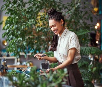 Empreendedora aplicando a sustentabilidade em seu negócio ao criar um arranjo com plantas e produtos ecológicos.