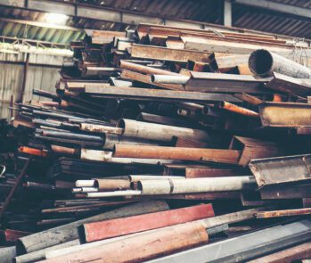 Depósito de sucata metálica com peças de ferro e aço armazenadas para reciclagem ou destinação ambientalmente adequada. Gestão de resíduos industriais conforme normas e legislações.