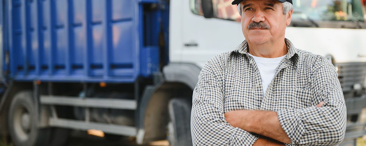 Imagem de um motorista de caminhão de transporte de resíduos, com expressão confiante, posicionado à frente de um caminhão de coleta. Representa a importância da logística e do controle no transporte de resíduos sólidos, seguindo normas ambientais e garantindo segurança e eficiência. Ideal para conteúdos relacionados a CTR (Controle de Transporte de Resíduos), gestão de resíduos industriais, sustentabilidade e regulamentação ambiental.