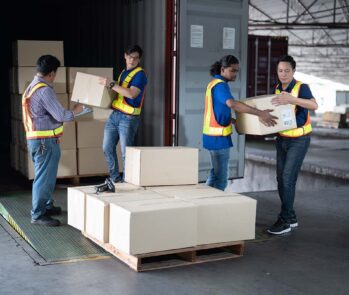 Operação de logística reversa com trabalhadores recebendo e conferindo caixas retornadas de um contêiner.