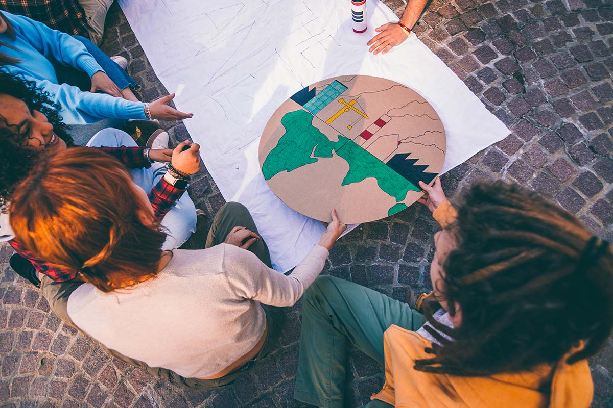 Jovens ativistas elaborando um projeto sobre desenvolvimento sustentável, ilustrando as diretrizes da sustentabilidade em um cartaz.
