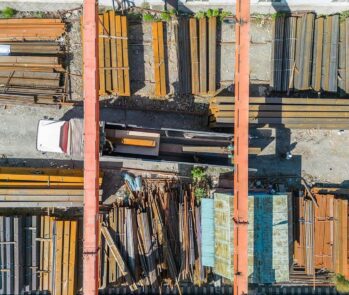 Vista aérea de pátio industrial com pilhas organizadas de resíduos metálicos e estrutura de armazenamento, ilustrando acondicionamento correto de materiais recicláveis