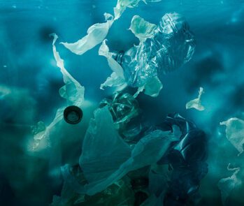 Resíduos plásticos submersos no oceano, representando a poluição marinha e seus impactos ambientais. A imagem evidencia a urgência na gestão adequada de resíduos sólidos para prevenir a contaminação de ecossistemas aquáticos e proteger a vida marinha.