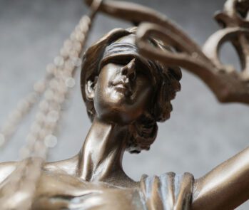 Imagem em close da estátua da deusa da justiça (Têmis), símbolo do direito e da imparcialidade, com foco no rosto vendado. Representa a legislação sobre resíduos sólidos, reforçando a importância do cumprimento das normas jurídicas e ambientais.