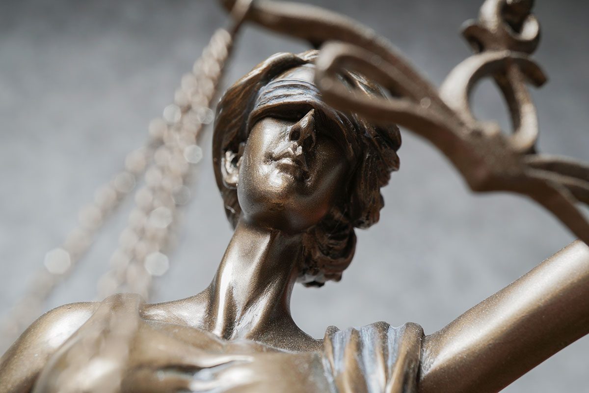 Imagem em close da estátua da deusa da justiça (Têmis), símbolo do direito e da imparcialidade, com foco no rosto vendado. Representa a legislação sobre resíduos sólidos, reforçando a importância do cumprimento das normas jurídicas e ambientais.