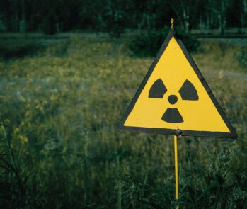 Sinal de advertência de radiação em área isolada, ilustrando os cuidados exigidos no manejo e descarte de resíduos radioativos. A imagem é ideal para conteúdos sobre legislação ambiental, segurança nuclear e gestão de resíduos perigosos no Brasil, especialmente no contexto das normas da CNEN e da Política Nacional de Resíduos Sólidos.