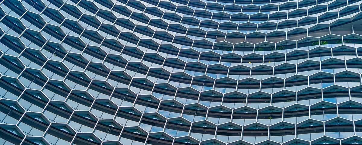 Fachada moderna de edifício com arquitetura em padrão hexagonal, simbolizando inovação, tecnologia e processos integrados end-to-end em gestão empresarial.