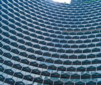 Fachada moderna de edifício com arquitetura em padrão hexagonal, simbolizando inovação, tecnologia e processos integrados end-to-end em gestão empresarial.