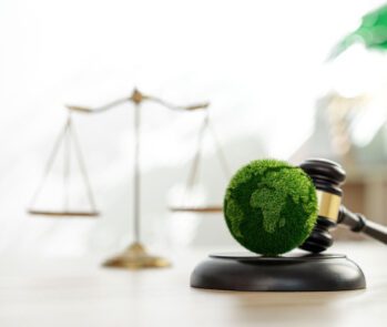 Símbolos da lei (martelo e balança) e do meio ambiente (globo verde), representando a legislação para o transporte de resíduos.