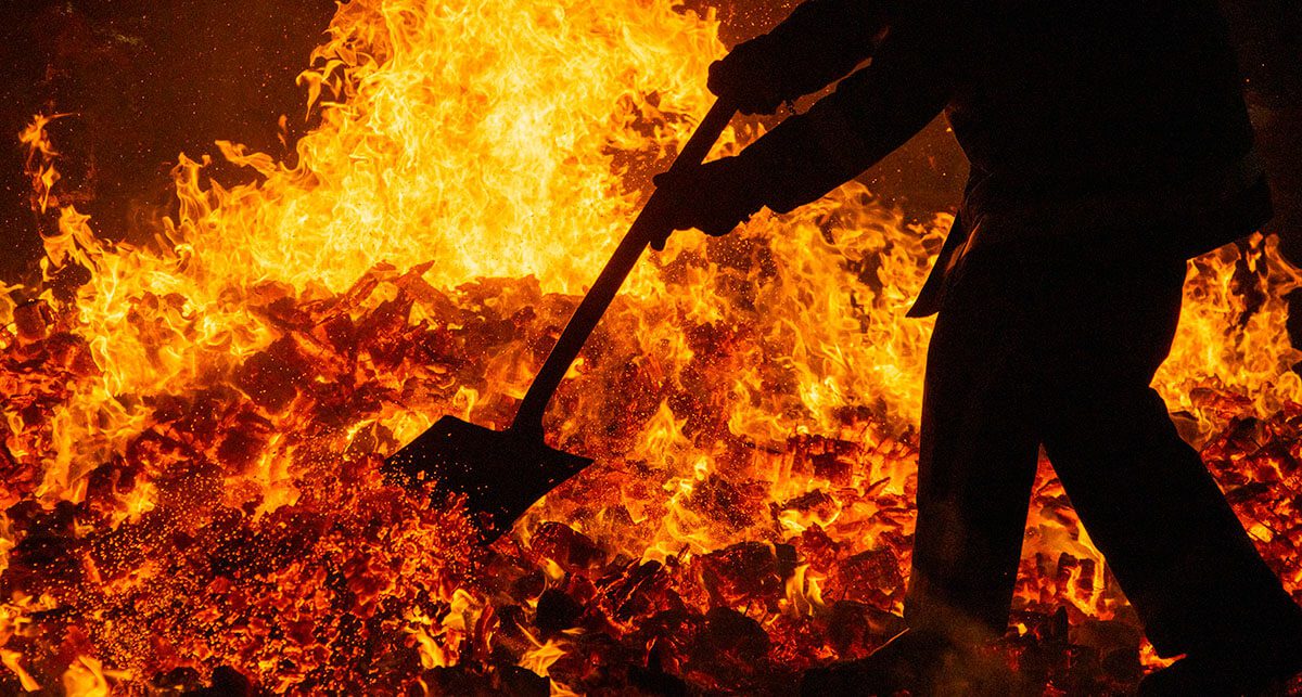 Profissional operando incinerador com chamas intensas durante o processo de incineração de resíduos sólidos. Gestão de resíduos, tratamento térmico e avaliação das vantagens e desvantagens da incineração do lixo.