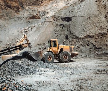 Máquinas pesadas operando em mina a céu aberto, ilustrando o manejo e a gestão de resíduos da mineração.