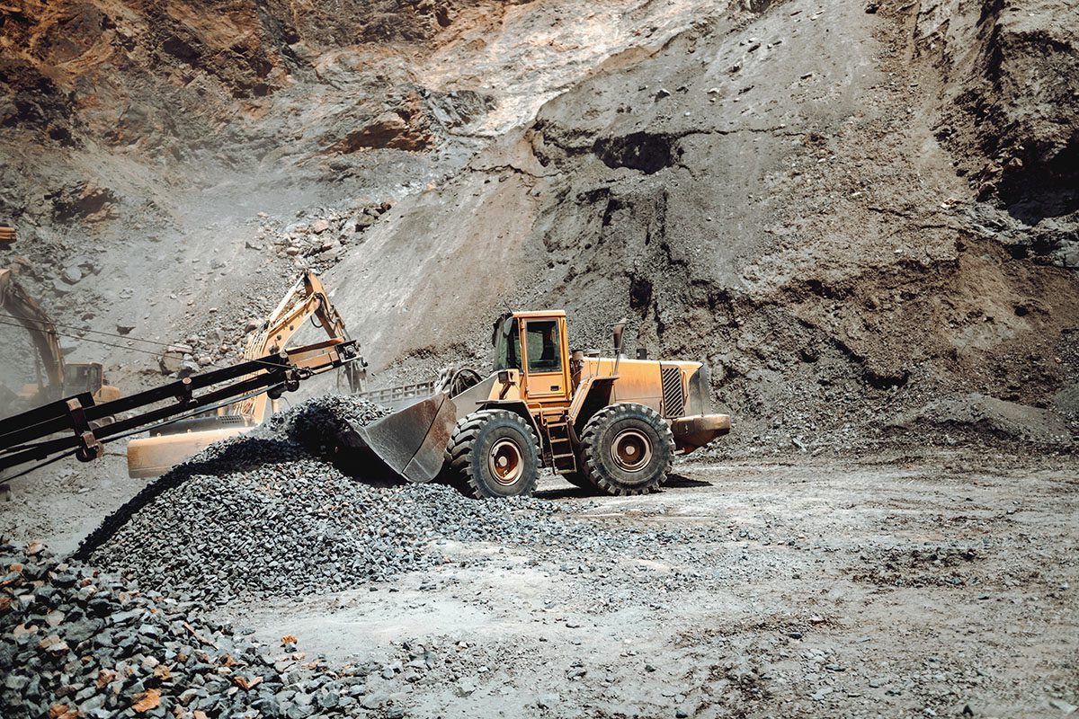 Máquinas pesadas operando em mina a céu aberto, ilustrando o manejo e a gestão de resíduos da mineração.