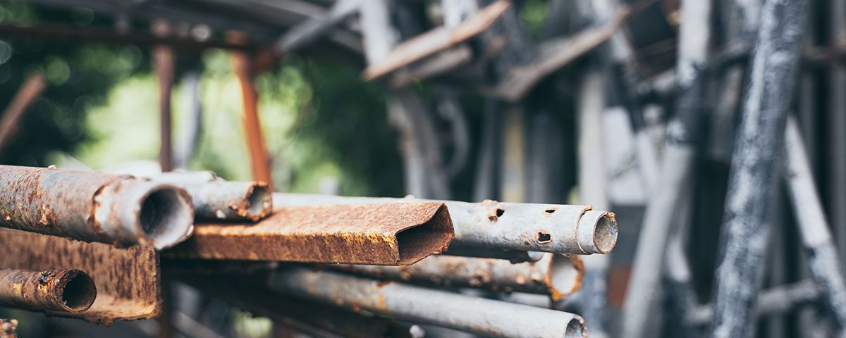 Pilhas de sucata metálica com tubos e chapas enferrujadas, representando os resíduos de sucatas mais comprados e vendidos no mercado de reciclagem.