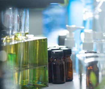Frascos de reagentes e vidrarias de laboratório com substâncias químicas, representando resíduos químicos laboratoriais e a importância da separação e destinação correta conforme normas ambientais.