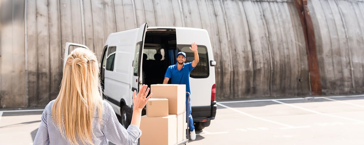 Profissional realizando coleta para logística reversa com van e caixas, enquanto cliente se despede no local de entrega.